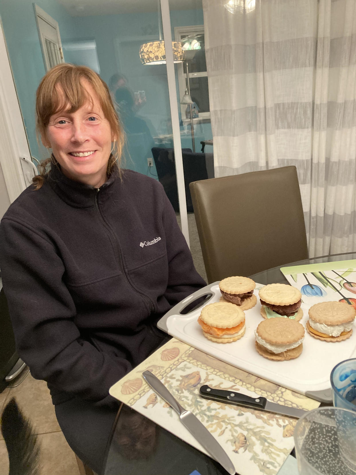 Woman smiling and sitting in black top and pants in front of desserts (Photo: Courtesy of Catherine Hoath)