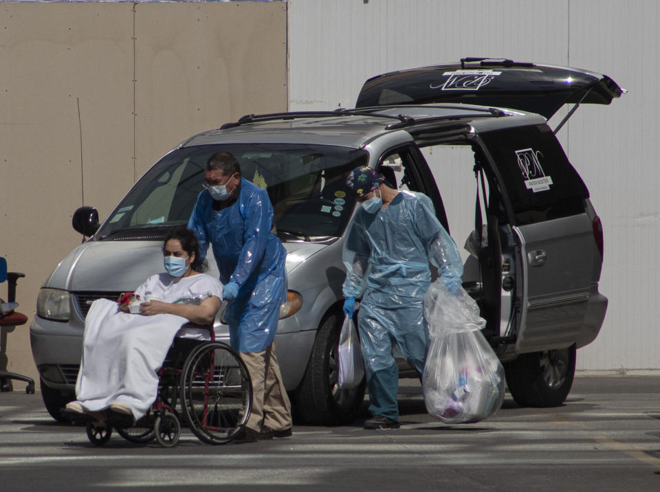 Trabajadores de salud con equipo de protección contra la propagación del COVID-19 empujan a una paciente en silla de ruedas frente a un carro funerario en el hospital San José en Santiago, Chile, el viernes 9 de abril de 2021. (AP Foto/Esteban Félix)