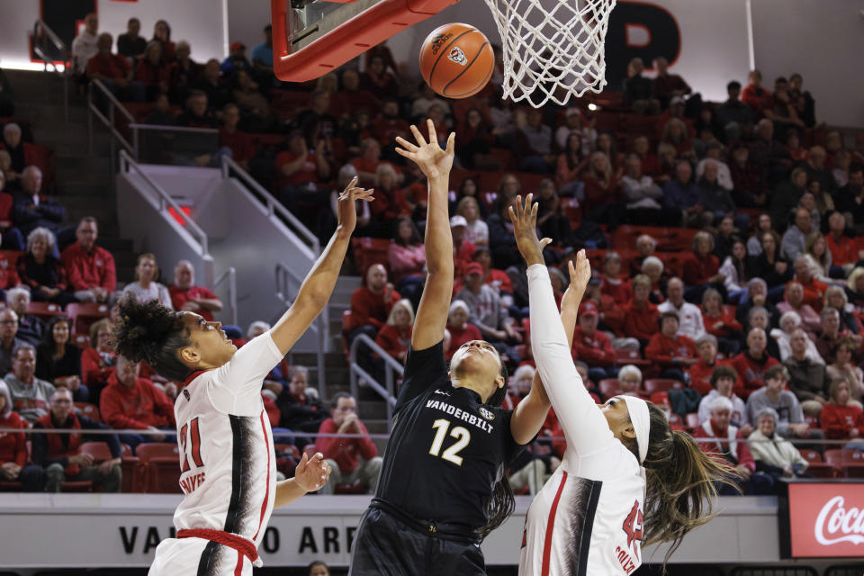 Vanderbilt's Khamil Pierre (12) attempts a shot between North Carolina State's Madison Hayes (21) and North Carolina State's Mallory Collier (42) during the first half of an NCAA college basketball game in Raleigh, N.C., Wednesday, Nov. 29, 2023. (AP Photo/Ben McKeown)