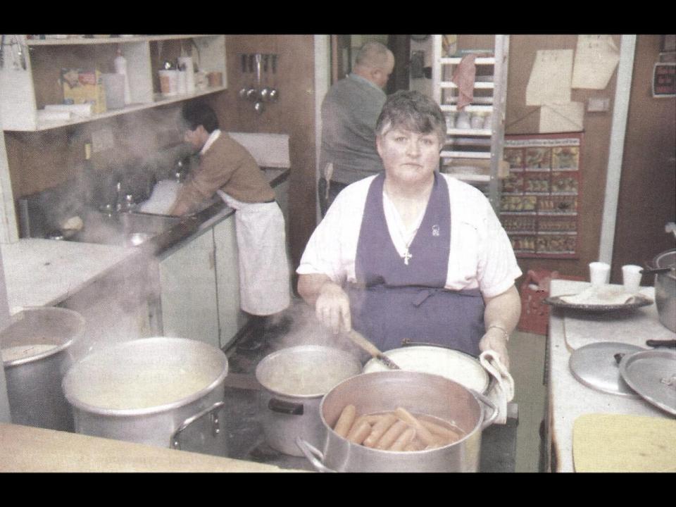 Romero House founder Carolyn McNulty, pictured cooking hot dogs at 42 Water Street, which the soup kitchen occupied before constructing a permanent home on Brunswick Drive in the early 1990s. 