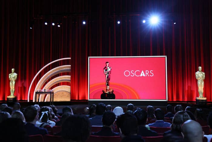 Stage with Oscar statue and "OSCARS" onscreen, with an audience in foreground