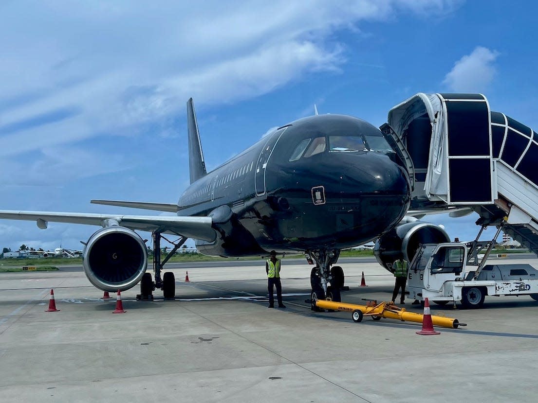 A black livery Beond plane sitting on the tarmac with airstairs attached.