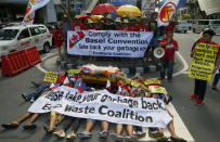 Environmentalists stage a mock die-in protest outside the Canadian Embassy to demand the Canadian government to speed up the removal of several containers of garbage that were shipped to the country Tuesday, May 21, 2019, in Manila, Philippines. The Philippines recalled its ambassador and consuls in Canada last week over Ottawa's failure to comply with a deadline to take back 69 containers of garbage that Filipino officials say were illegally shipped to the Philippines years ago. (AP Photo/Bullit Marquez)