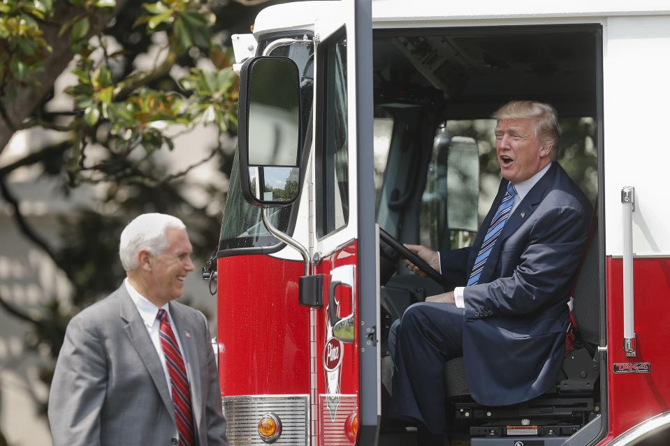 President Donald Trump, accompanied by Vice President Mike Pence, sits inside a cabin of a firetruck during a