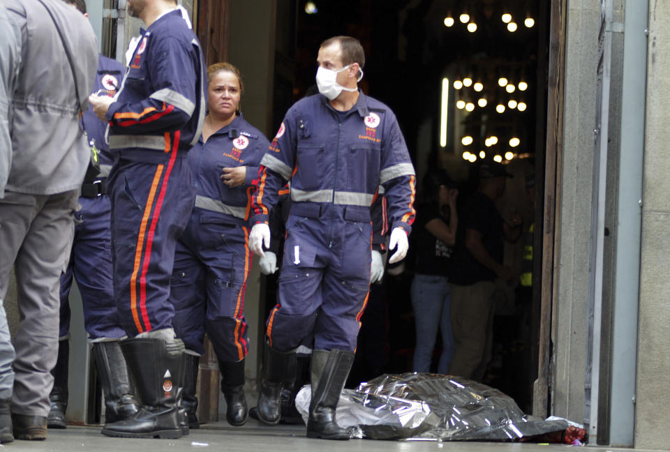 A firefighter walks next to a victim killed at the Metropolitan Cathedral in Campinas, Brazil, Tuesday, Dec.11, 2018. Authorities say an armed man entered the cathedral in southern Brazil on Tuesday afternoon and opened fire, killing at least four people before killing himself. (Denny Cesare/Futura Press via AP)