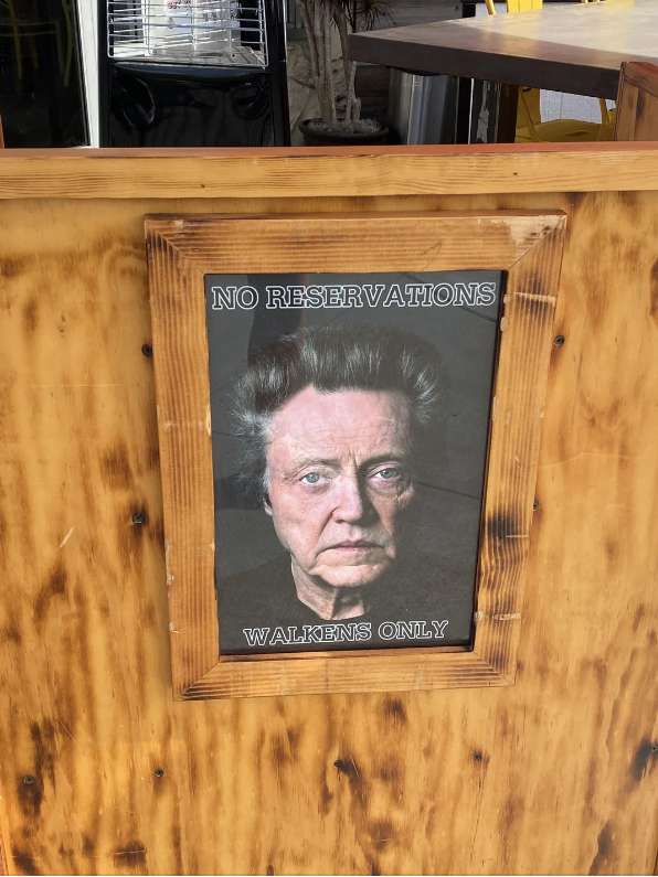 Sign on a restaurant stating "NO RESERVATIONS - WALKENS ONLY" with a portrait of Christopher Walken