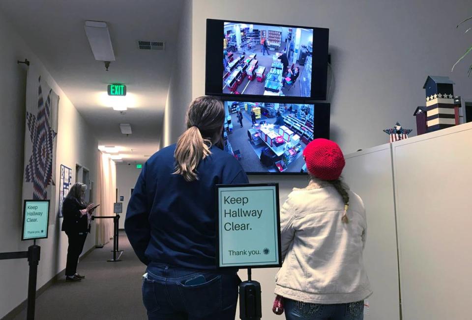 A Shasta County election worker, left, and an observer, watch workers on television monitors prepare the office before stopping work on election night, Tuesday, Nov. 8, 2022.