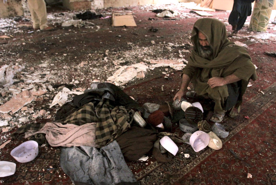 A Pakistani examines the remains of the victims at the site of Friday's bomb explosion inside a mosque in Quetta, Pakistan, Saturday, Jan. 11, 2020. A powerful explosion ripped through a mosque in Quetta, the provincial capital of Baluchistan province, during the evening prayers on Friday, killing a senior police officer and other some people and wounded many worshipers. (AP Photo/Arshad Butt)