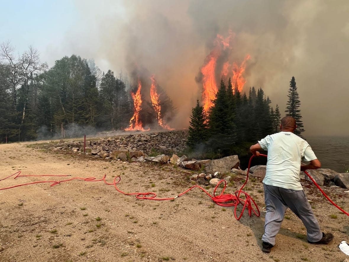 People work to protect cabins on Algonquins of Barriere Lake territory in Quebec earlier this week. Between 20 and 25 firefighters and concerned community members remain in the Algonquin community of Rapid Lake to combat and monitor forest fires impacting their traditional territory. (Submitted by Wendy Ratt - image credit)