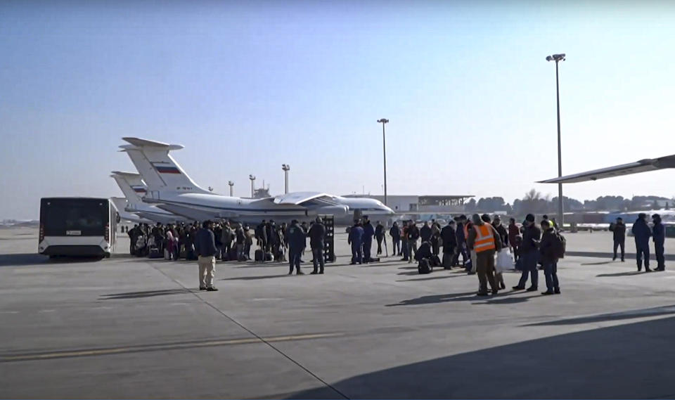 In this handout photo released by the Russian Defense Ministry Press Service, passengers gather to board the Russian Military Il-76 cargo planes at the airport in Kabul, Afghanistan, Saturday, Dec. 18, 2021. Russian military transport planes have delivered a shipment of humanitarian supplies to Afghanistan and flew back 200 Russians, Afghan students and others. The Russian Defense Ministry said that three Il-76 cargo planes will make stopover in Tajikistan and Kyrgyzstan before flying to Moscow. (Russian Defense Ministry Press Service via AP)