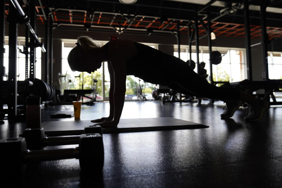 Marie Kadlec, of Rochester Hills., excercises at Burn Fitness in Rochester Hills, Mich., Monday, June 21, 2021. Michigan is fully open again. After facing 15 months of capacity restrictions and being hit by the country’s worst surge of coronavirus infections this spring, restaurants, entertainment businesses and other venues can operate at 100% occupancy starting Tuesday. (AP Photo/Paul Sancya)