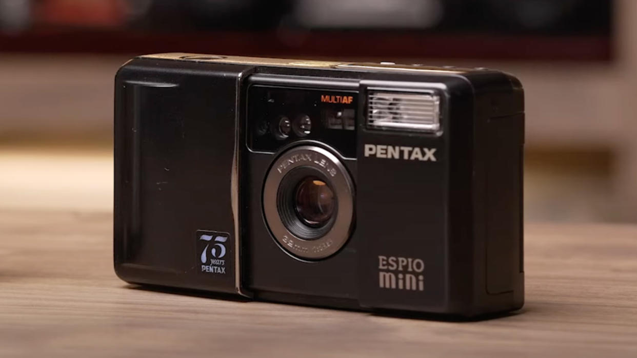  A Pentax Espio Mini film camera sitting on a table. 