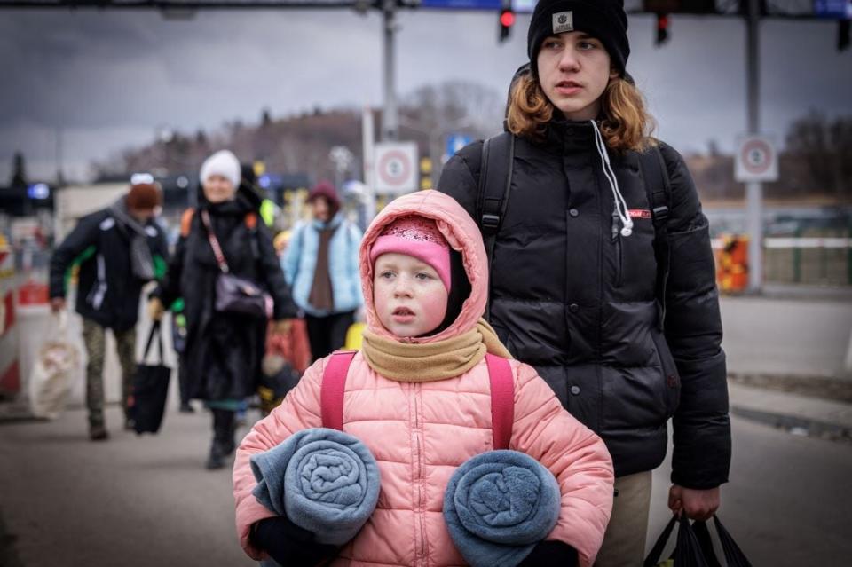 Two Ukrainian refugees cross into Poland from Ukraine carrying only blankets and a small bag. They look towards the humanitarian relief that welcomed them in Medyka, Poland on March 5, 2022.