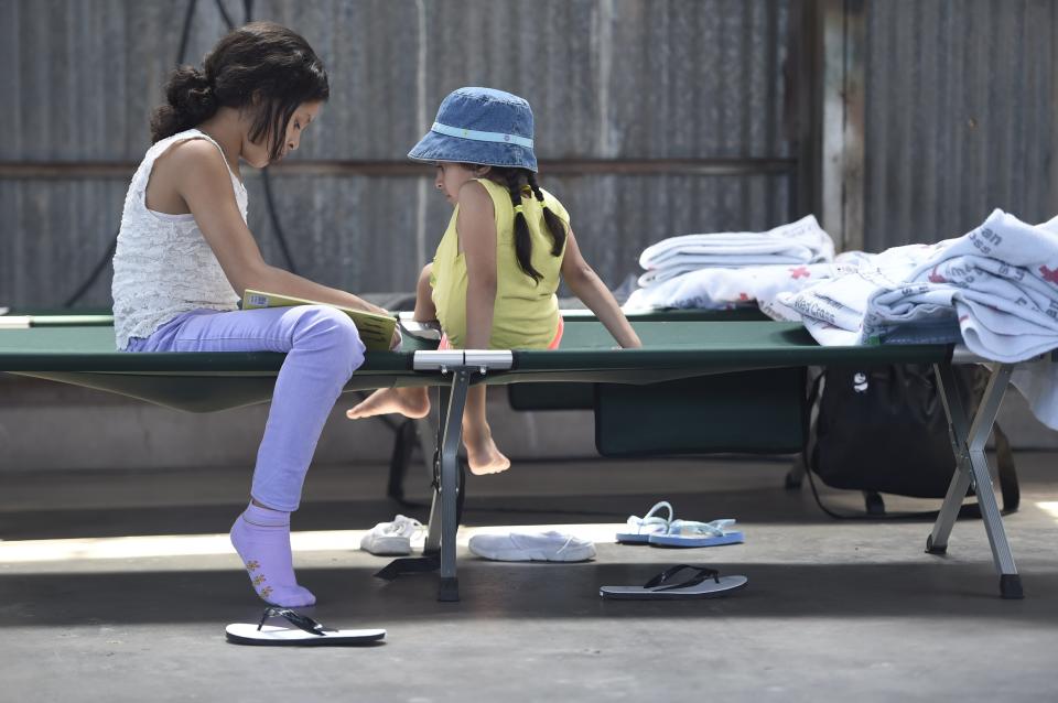 Two migrant children read on a cot in a migrant shelter June 28, 2019, in Deming, N.M.