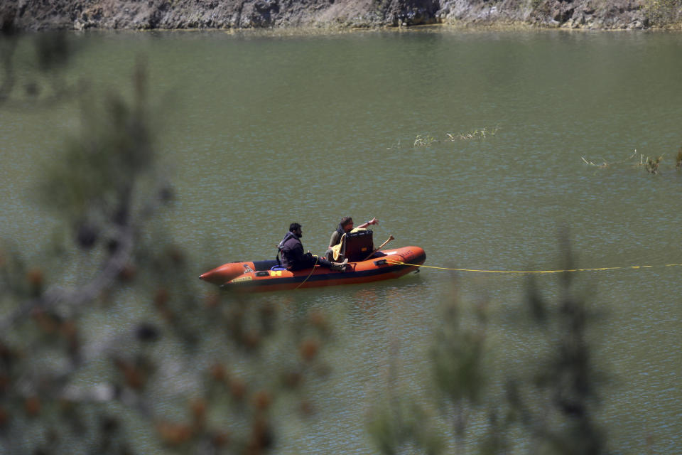 Investigators on a boat use a camera to search for a body in a lake near Xiliatos, after authorities found two female bodies in a flooded mineshaft, outside of Mitsero village, near capital Nicosia, Cyprus, Monday, April 22, 2019. Police on the east Mediterranean island nation, along with the help of the fire service, are conducting the search Monday in the wake of last week's discovery of the bodies in the abandoned mineshaft and the disappearance of the six year-old daughter of one of the victims. (AP Photo/Philippos Christou)