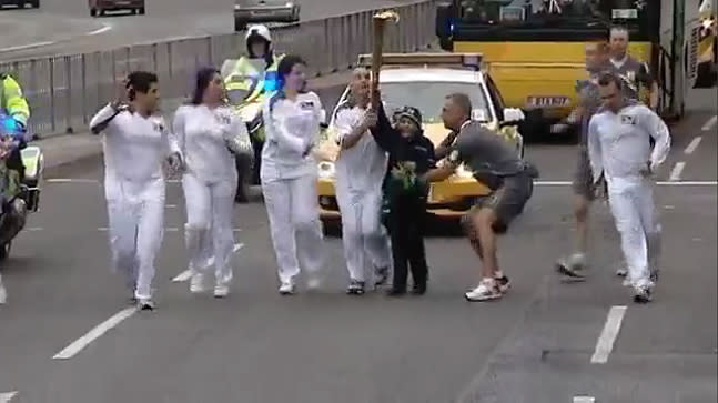 In this video still from July 2, the 47th day of the Olympic Torch Relay, two children briefly grabbed the Olympic Torch away from the torchbearer as he ran through Coventry. (Reuters)