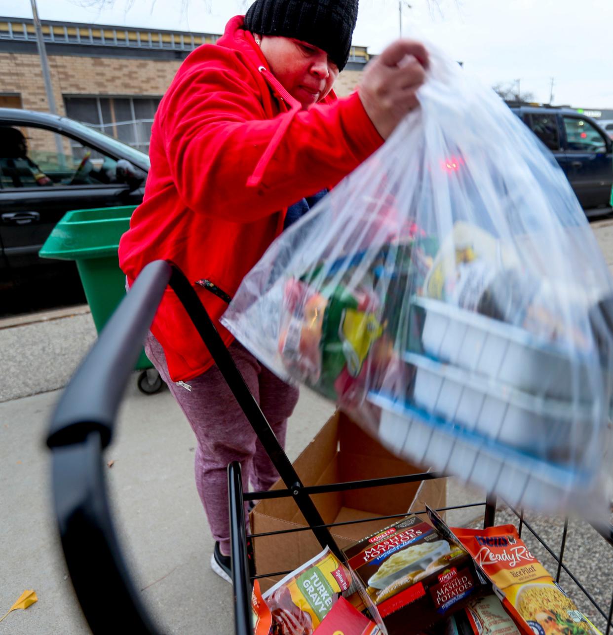 Maria Ulla places food courtesy of Feeding America Eastern Wisconsin into her cart during a food drive Thursday, Nov. 18, 2021, at Forest Home Avenue School in Milwaukee. The school hosts a food drive once a month to help feed families in need whether students go to the school or if they are members of the community.