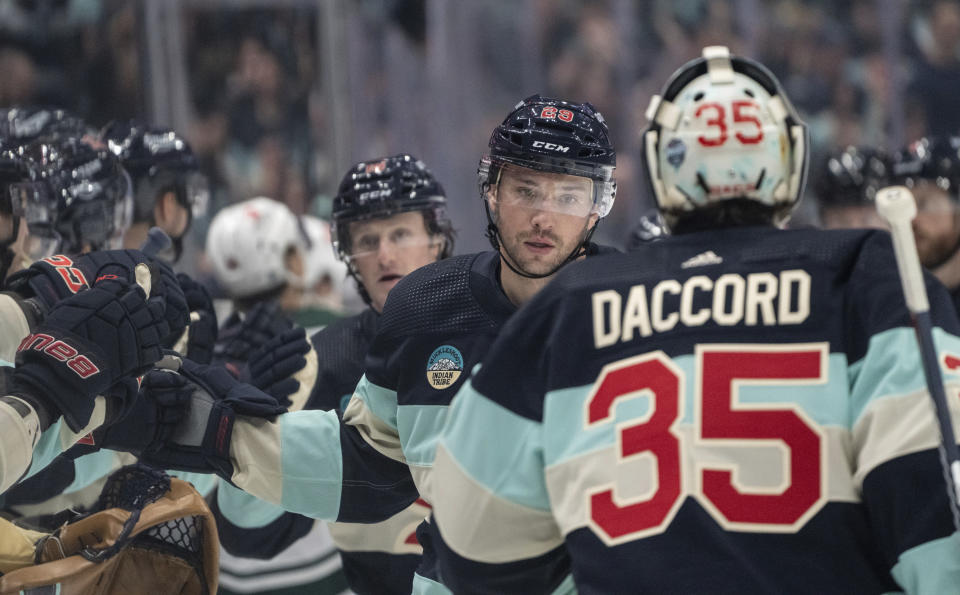Seattle Kraken defenseman Vince Dunn, second from right, is congratulated by teammates, including goalie Joey Daccord, right, after scoring during the first period of an NHL hockey game against the Minnesota Wild, Saturday, Feb. 24, 2024, in Seattle. (AP Photo/Stephen Brashear)