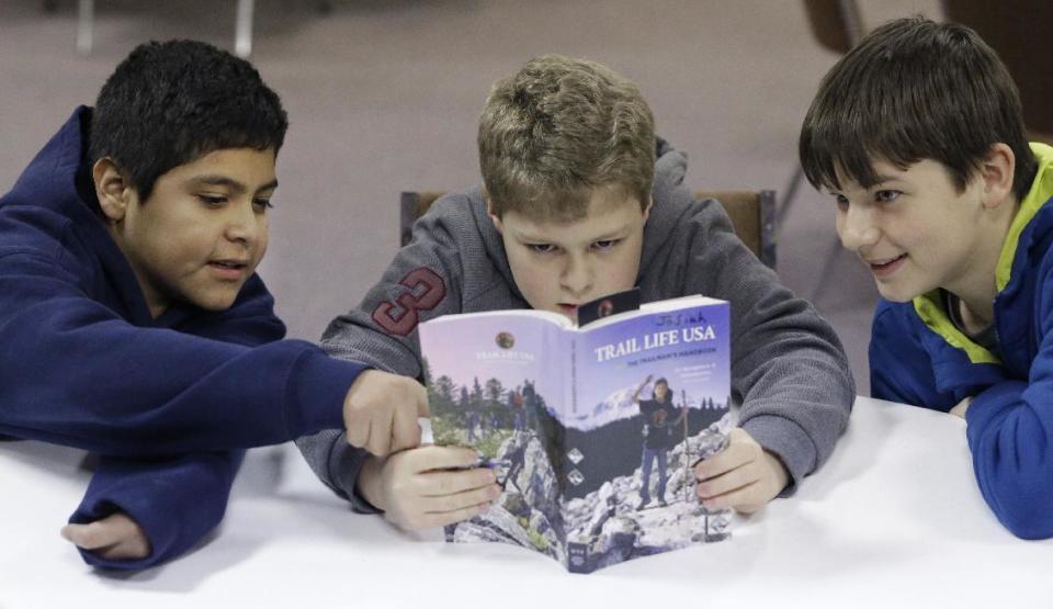 In this Tuesday, Feb. 4, 2014 photo, from left, Erick Izquierdo, Josiah Spear, 12, and Cole McSorley, 12, look at a Trail Life handbook during a gathering of members in North Richland Hills, Texas. Trail Life USA says it has established units in more than 40 states, mostly from Boy Scouts and parents who feel the century-old organization has lost its way. (AP Photo/LM Otero)