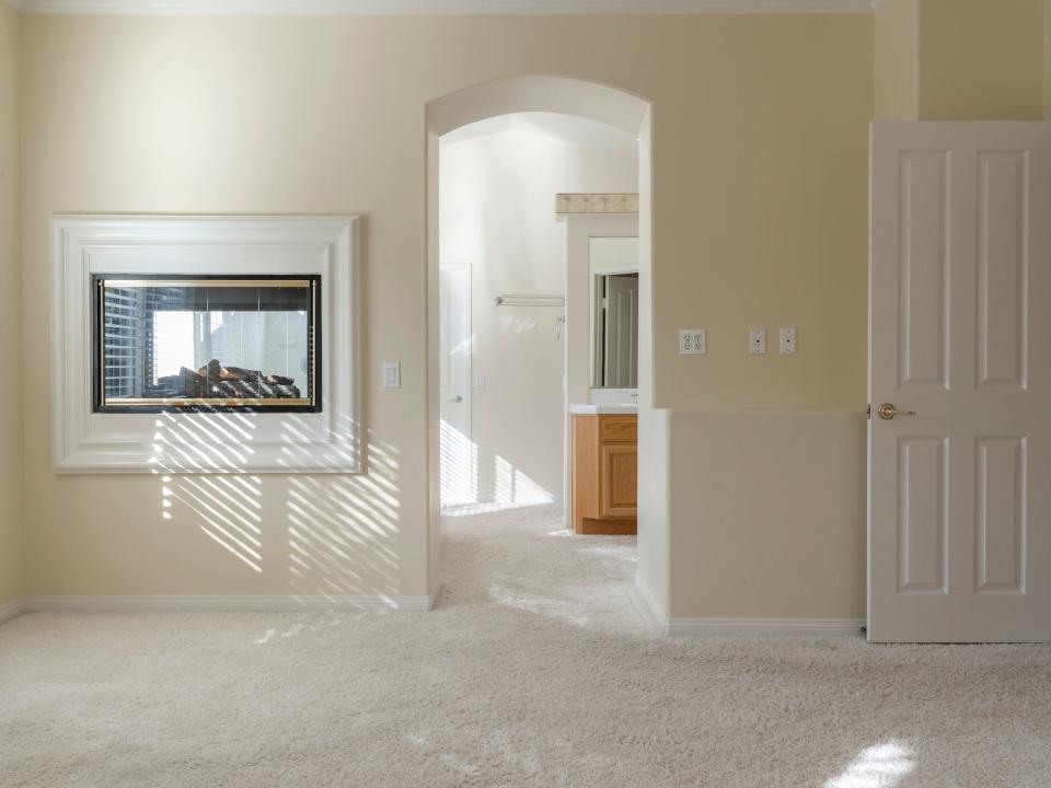 A yellow wall with a fireplace leading to a bathroom.