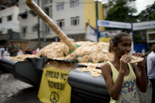 A girl eats bread next to a fake tank covered with bread on display to protest against the weapon market in the Santa Marta shantytown. After exhausting negotiations concluding on the eve of a global summit, UN members on Tuesday backed a plan for nursing Earth's sick environment back to health and tackling poverty through greener growth