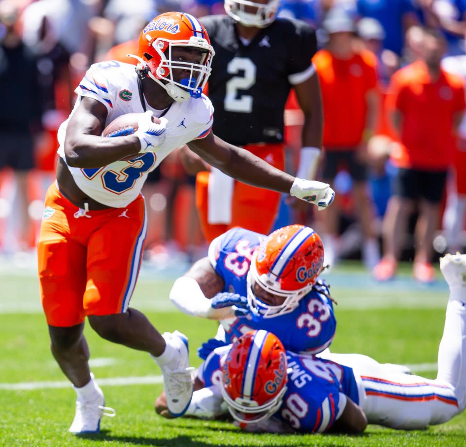 Florida Gators running back Jadan Baugh (13) eludes a tackle by Florida Gators edge rusher Brien Taylor Jr. (33) in the first half during the Orange and Blue game at Ben Hill Griffin Stadium in Gainesville, FL on Saturday, April 13, 2024 [Doug Engle/Gainesville Sun]2024