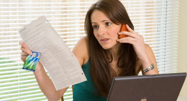 worried woman on phone checking  credit card / bank statement / bills