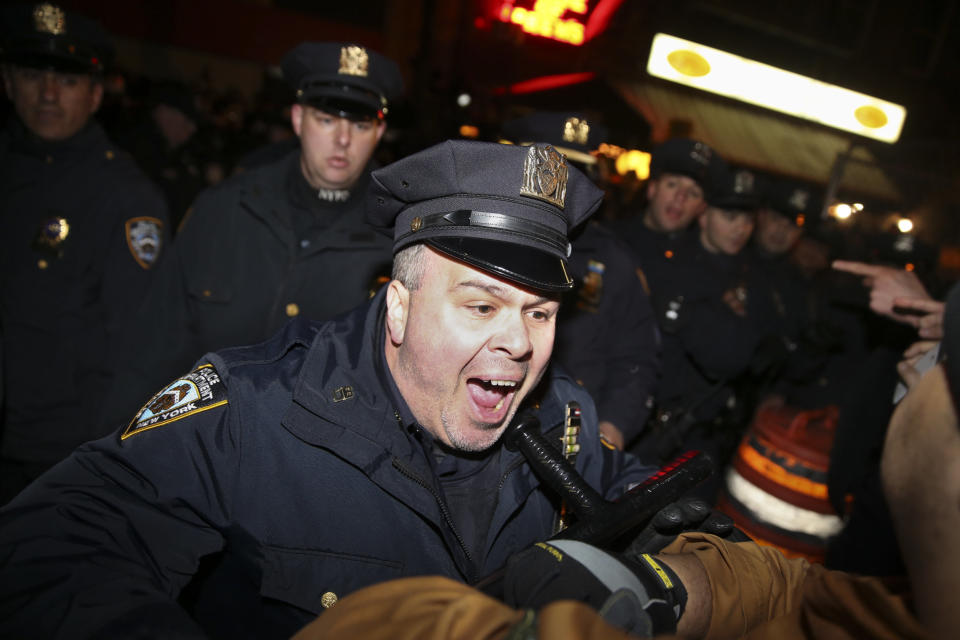 A police officer reacts as he pushes protestors away from an arrest during a march against a grand jury's decision not to indict the police officer involved in the death of Eric Garner, Friday, Dec. 5, 2014, in New York.  (AP Photo/John Minchillo)