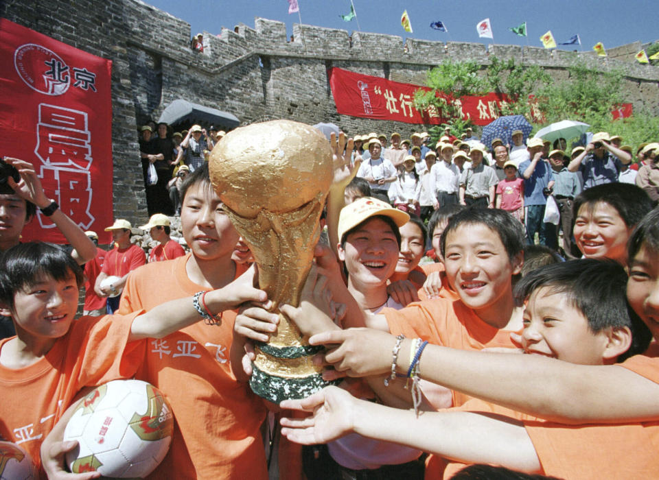 FILE - Chinese children pose with a replica of the World Cup trophy on the Great Wall of China at Jinshanling during an event to show their support for the Chinese national soccer team Saturday, May 25, 2002. China is missing out on the World Cup again despite spending millions — probably billions — to develop the game, a reported priority of Xi Jinping, the all-powerful general secretary of the Chinese Communist Party. (AP Photo/str, File)