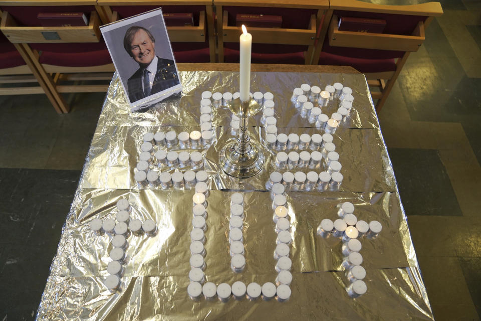 Candles and a photo at a vigil at St Michael & All Angels church in Leigh-on-Sea in Essex, England, Sunday Oct. 17, 2021 for Conservative MP Sir David Amess who died after he was stabbed several times at a constituency surgery on Friday. (Kirsty O'Connor/PA via AP)