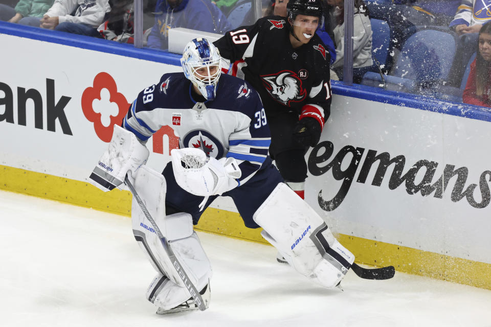 Winnipeg Jets goaltender Laurent Brossoit (39) plays the puck past Buffalo Sabres center Peyton Krebs (19) during the third period of an NHL hockey game Sunday, March 3, 2024, in Buffalo, N.Y. (AP Photo/Jeffrey T. Barnes)