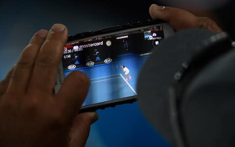 A spectator takes a photo of Federer during the match - Credit: AFP