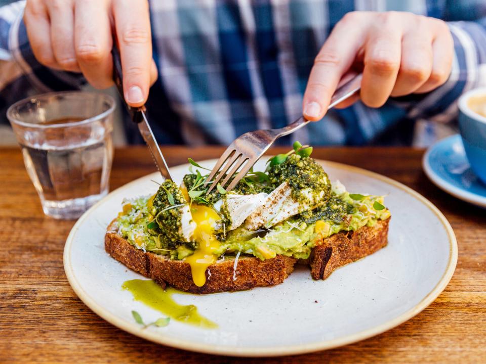 A man eating avocado toast with a poached egg.