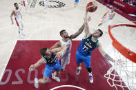 Slovenia's Luka Doncic (77) and Vlatko Cancar, left, fight for a rebound with Spain's Willy Hernangomez, center, during a men's basketball preliminary round game at the 2020 Summer Olympics, Sunday, Aug. 1, 2021, in Saitama, Japan. (Charlie Neibergall/Pool Photo via AP)