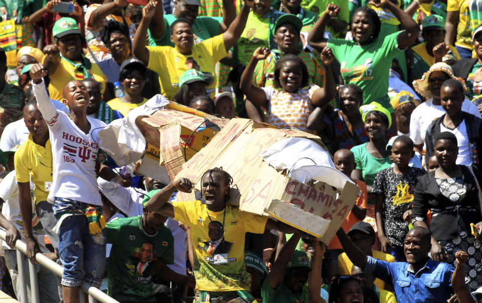 Supporters of Zimbabwean President Emmerson Mnangagwa carry a makeshift coffin bearing the name of opposition leader Nelson Chamisa during Mnangagwa's inauguration ceremony at the National Sports Stadium in Harare, Sunday, Aug. 26, 2018. Zimbabwe on Sunday inaugurated a president for the second time in nine months as a country recently jubilant over the fall of longtime leader Robert Mugabe is now largely subdued by renewed harassment of the opposition and a bitterly disputed election. (AP Photo/Tsvangirayi Mukwazhi)