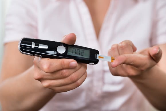 A woman using a glucometer to test her blood sugar level.