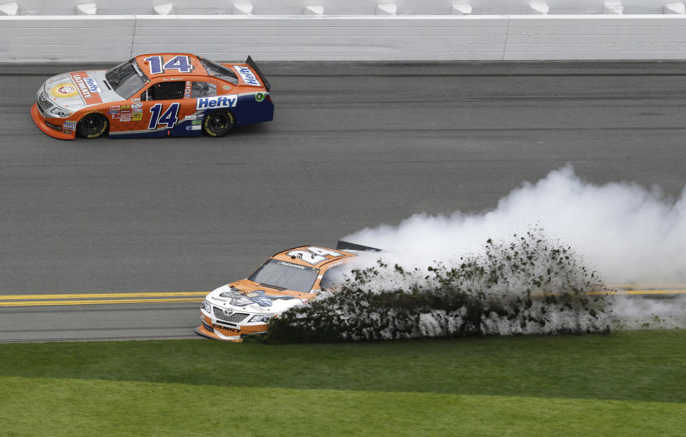 Grass flies as Harrison Rhodes (24) spins during the NASCAR Nationwide series auto race at Daytona International Speedway in Daytona Beach, Fla., Saturday, Feb. 22, 2014. Eric McClure (14) drives past at top. (AP Photo/John Raoux)