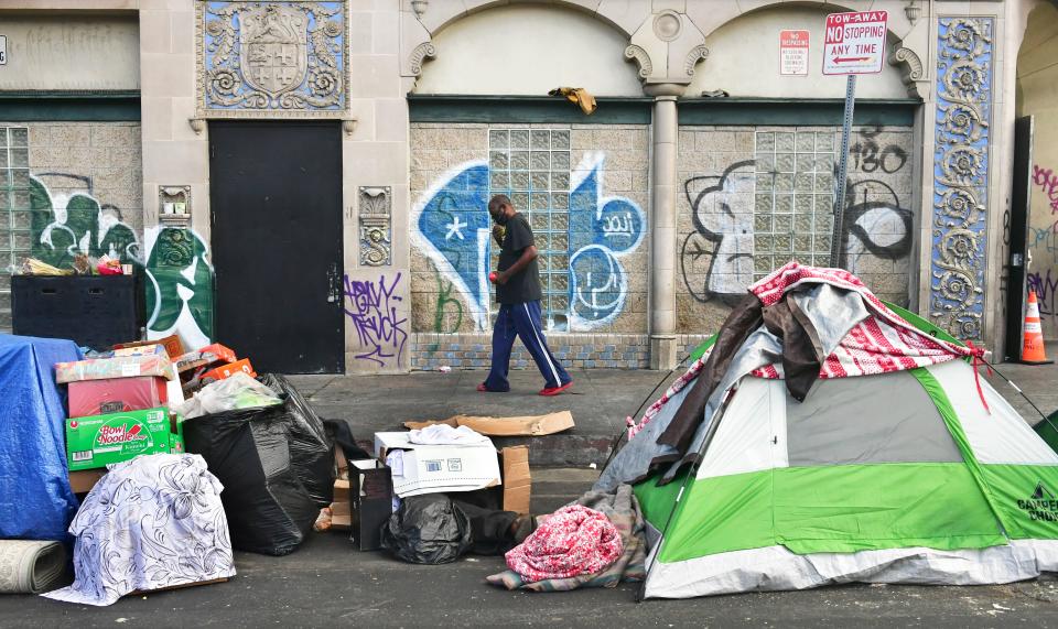 A man walks past tents housing the homeless on the streets in the Skid Row community of Los Angeles.