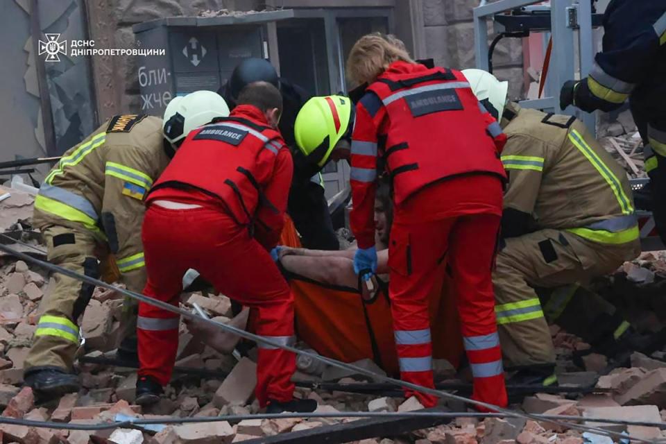 Rescuers and ambulance workers carry a person on the scene of a Russian attack in Dnipro (AP)