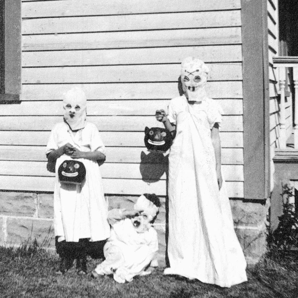 <p>A trio of kids dress up like ghosts for trick or treating in 1925. </p>