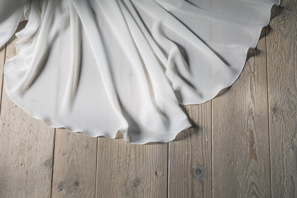 Part of a wedding dress lying on a wooden floor