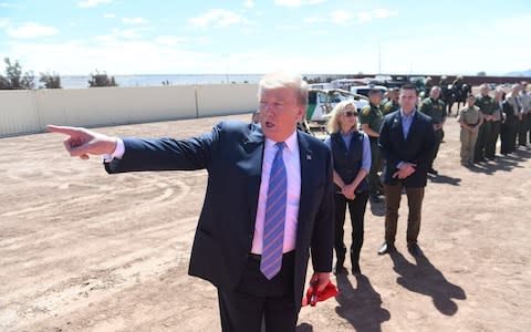 US President Donald Trump speaks with members of the US Customs and Border Patrol as he tours the border wall between the United States and Mexico  - Credit: Saul Loeb/AFP