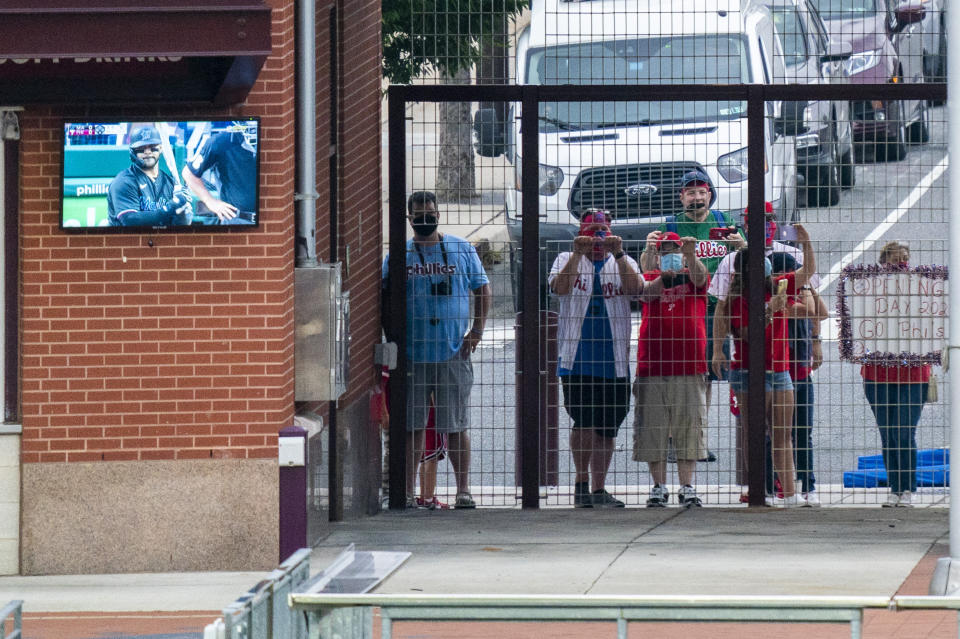 Philadelphia Phillies' fans watch from the gate outside of the stadium just past center field during the first inning of a baseball game against the Miami Marlins, Friday, July 24, 2020, in Philadelphia. (AP Photo/Chris Szagola)