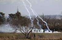 Greek soldiers and riot police officers stand guard as tear gas is being fired near Turkey's Pazarkule border crossing, in Kastanies