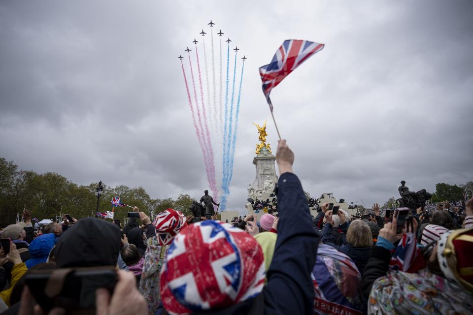 People watch the fly past as Britain’s King Charles III and Queen Camilla wave to the crowds from the balcony of Buckingham Palace after the coronation ceremony in London.