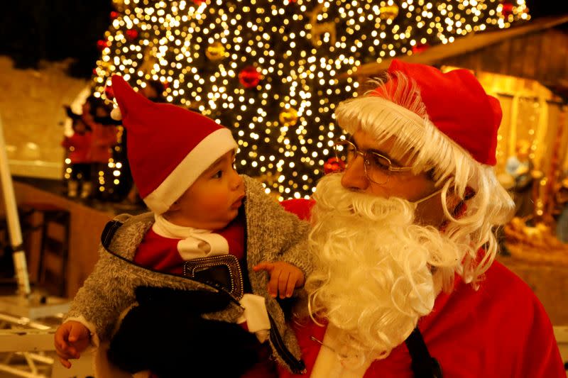 A man dressed as Santa Claus holds a baby at Manger Square in Bethlehem in the Israeli-occupied West Bank