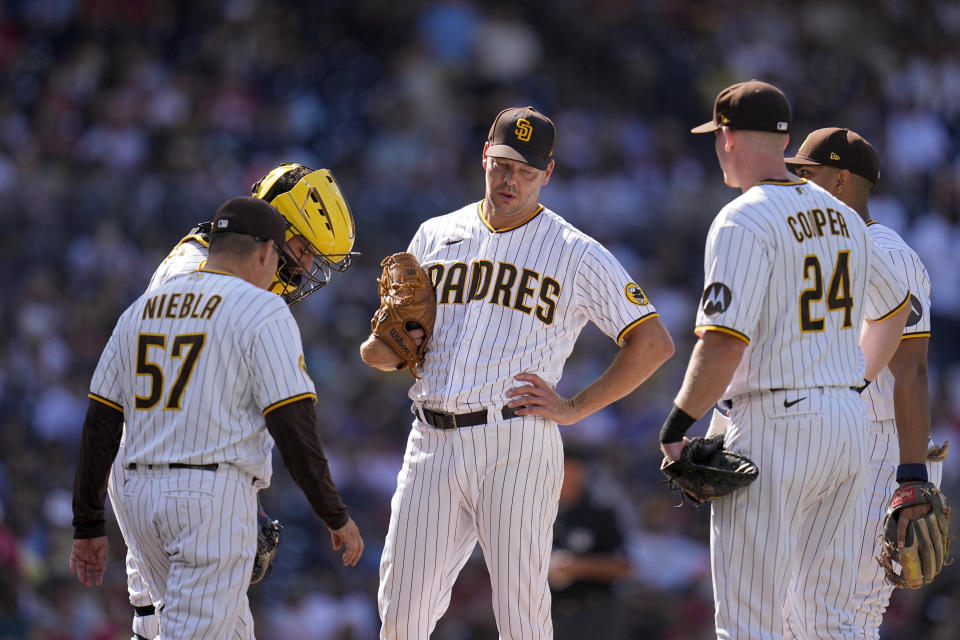 San Diego Padres starting pitcher Rich Hill, center, looks on in a mound visit with pitching coach Ruben Niebla (57) and infielders during the first inning of a baseball game against the Philadelphia Phillies, Monday, Sept. 4, 2023, in San Diego. (AP Photo/Gregory Bull)