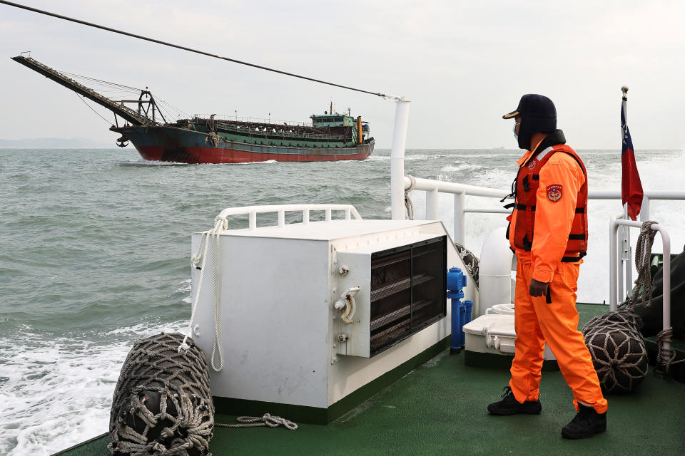 Image: A Taiwanese coast guard looks at a sand-dredging ship with a Chinese flag in the waters off the Taiwan-controlled Matsu islands, on Jan. 28, 2021. (Ann Wang / Reuters)