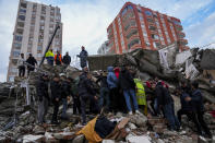 People and emergency teams search for people through the rubble of a destroyed building in Adana, Turkey, Monday, Feb. 6, 2023. A powerful quake has knocked down multiple buildings in southeast Turkey and Syria and many casualties are feared. (AP Photo/Khalil Hamra)