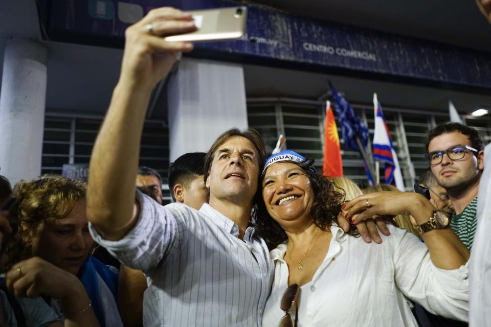 Uruguay's presidential candidate for the National Party Luis Lacalle Pou,takes a selfie with a supporter at the end of the campaign closing rally in Las Piedras, Uruguay, Wednesday, Nov. 20, 2019. Uruguay will hold run-off presidential elections on Nov. 24 between presidencial candidate for the National Party, Luis Lacalle Pou and Daniel Martinez, of the ruling party Broad Front. (AP Photo/Matilde Campodonico)